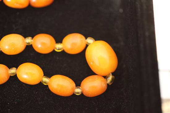 A single strand graduated oval amber necklace with yellow paste spacers, 15.5in.
